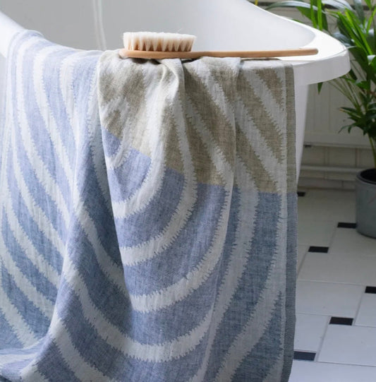 Striped towel draped over a bathtub with a brush on top, in a bathroom setting.